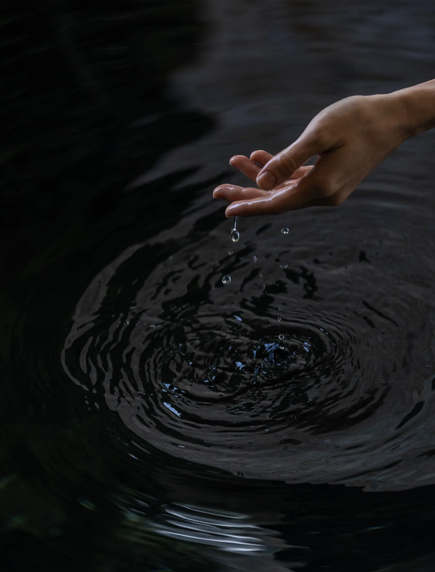 A hand above rippling water, Layan Life by Anantara